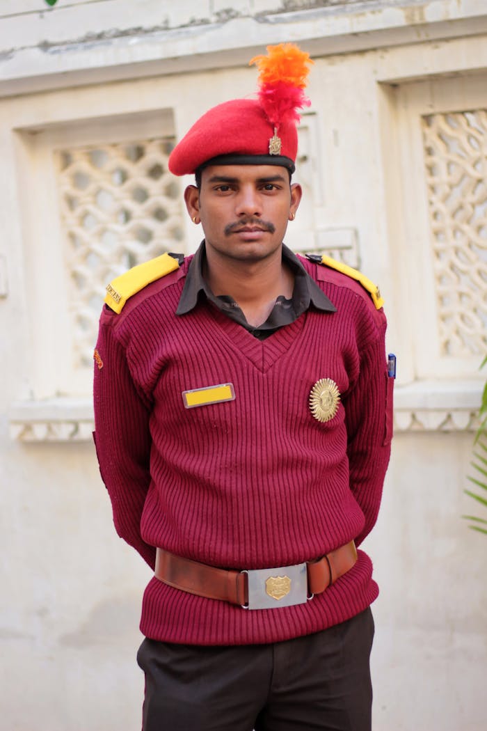 A security guard in uniform posing confidently with a red beret and badge.
